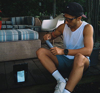 Man grinding coffee on a porch with a manual coffee grinder