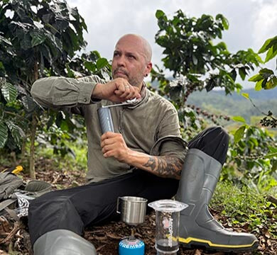Man sitting in a coffee plantation with coffee-making equipment