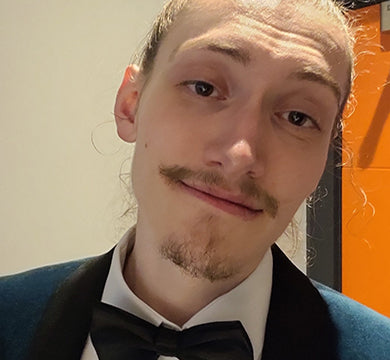 Person wearing a black bow tie against a neutral background