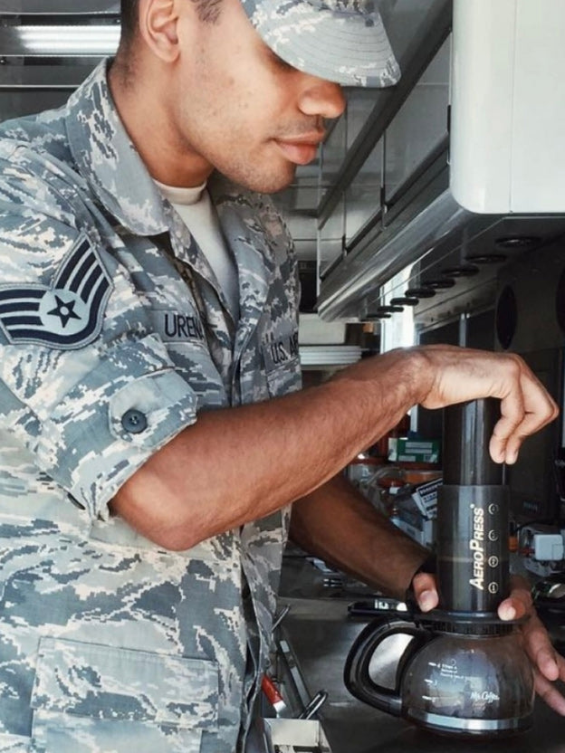 Military man in camo clothing brewing AeroPress Original