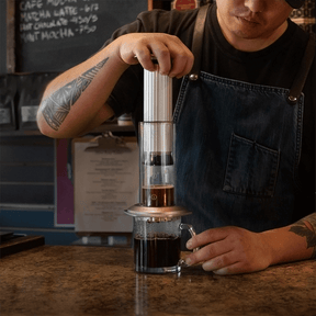 Person brewing with AeroPress Premium in cafe