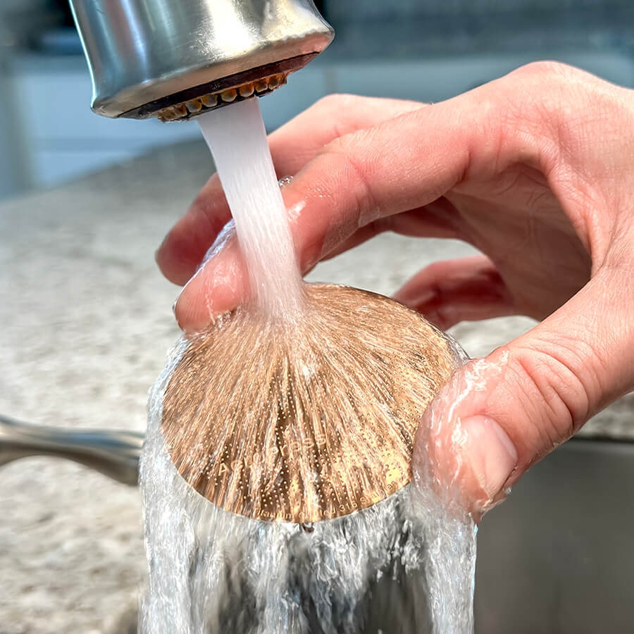 Person rinsing the Gold Tone Filter in the sink