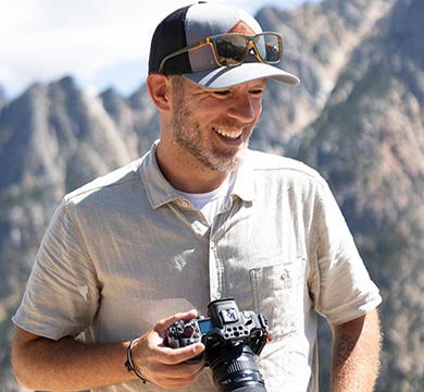 Man holding a camera with mountains in the background