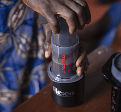Person using an AeroPress coffee press on a wooden surface