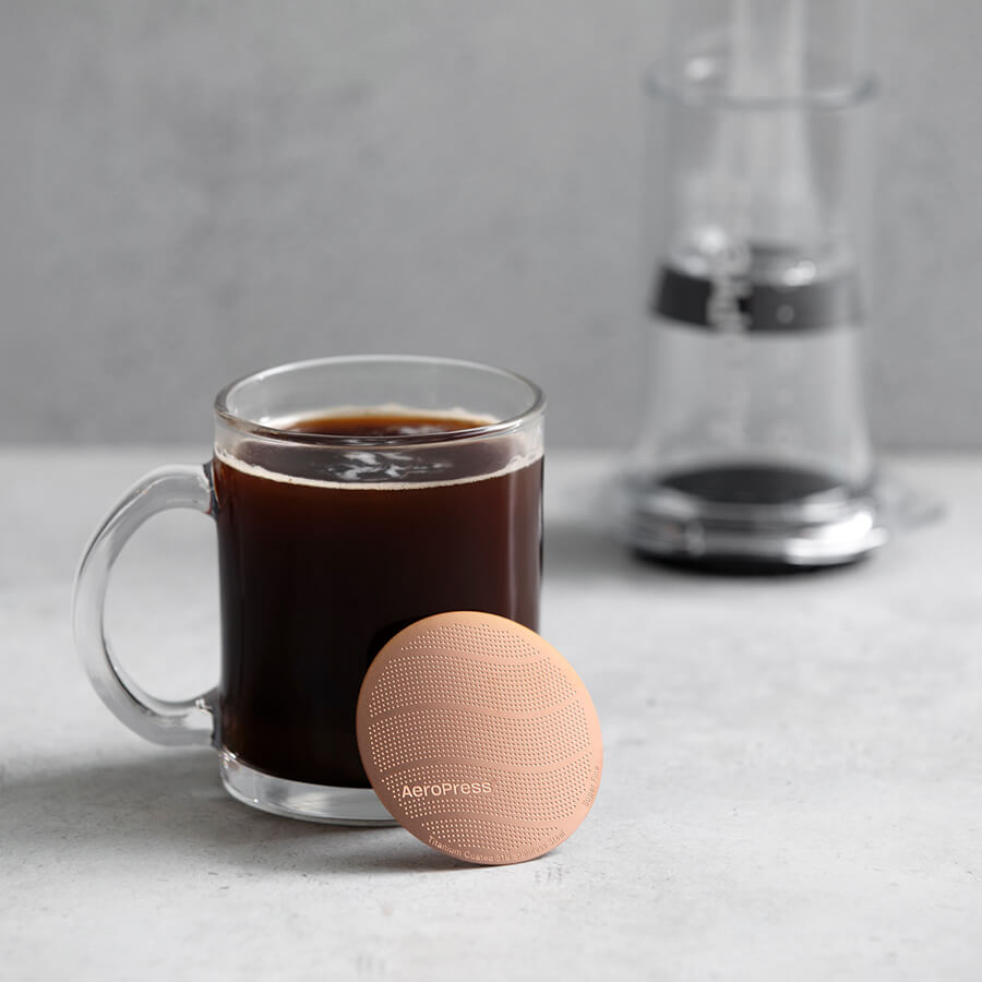 Gold Tone Filter leaning against cup of coffee