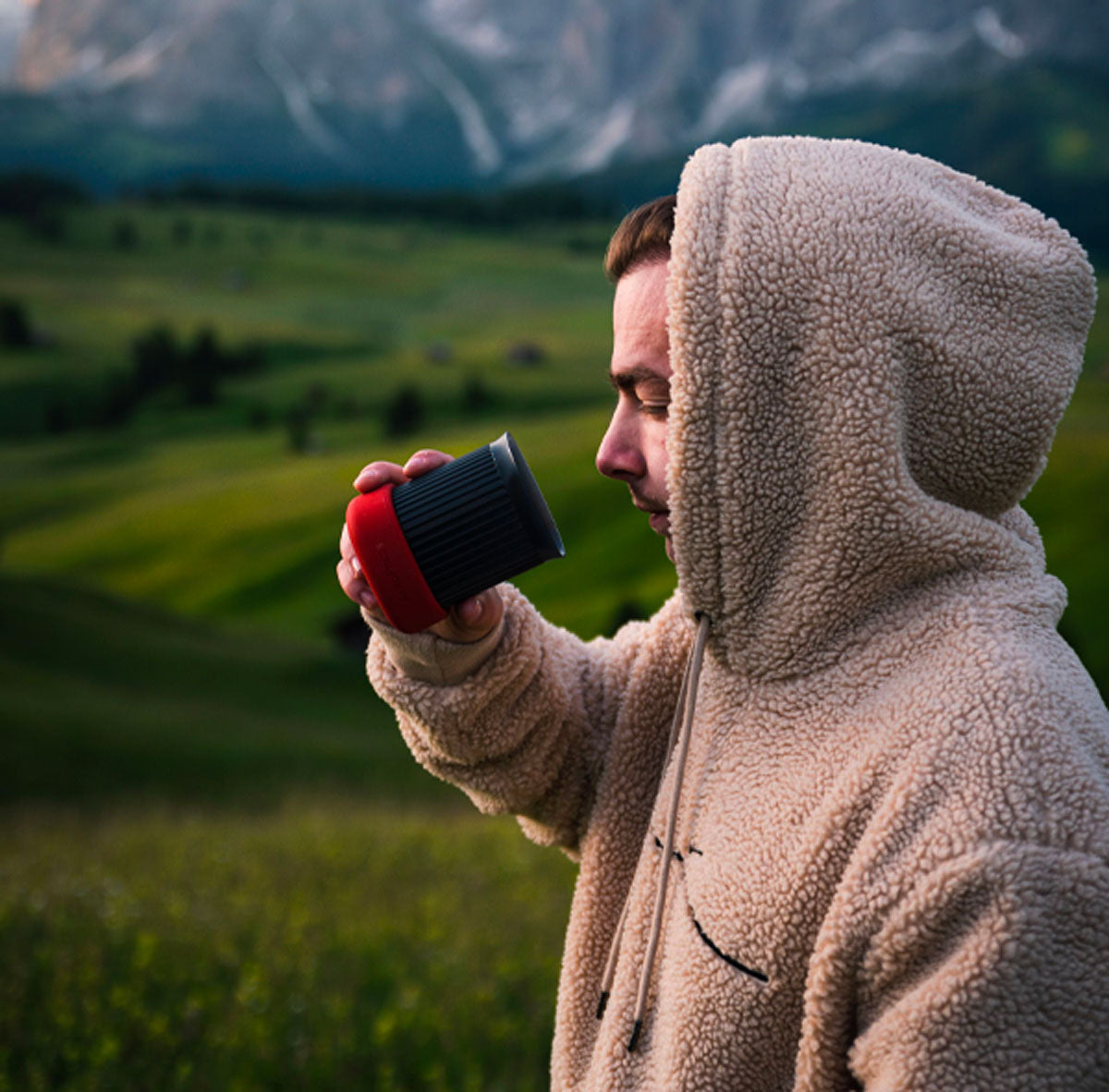 Man in sweater drinking coffee from AeroPress Go mug outdoors