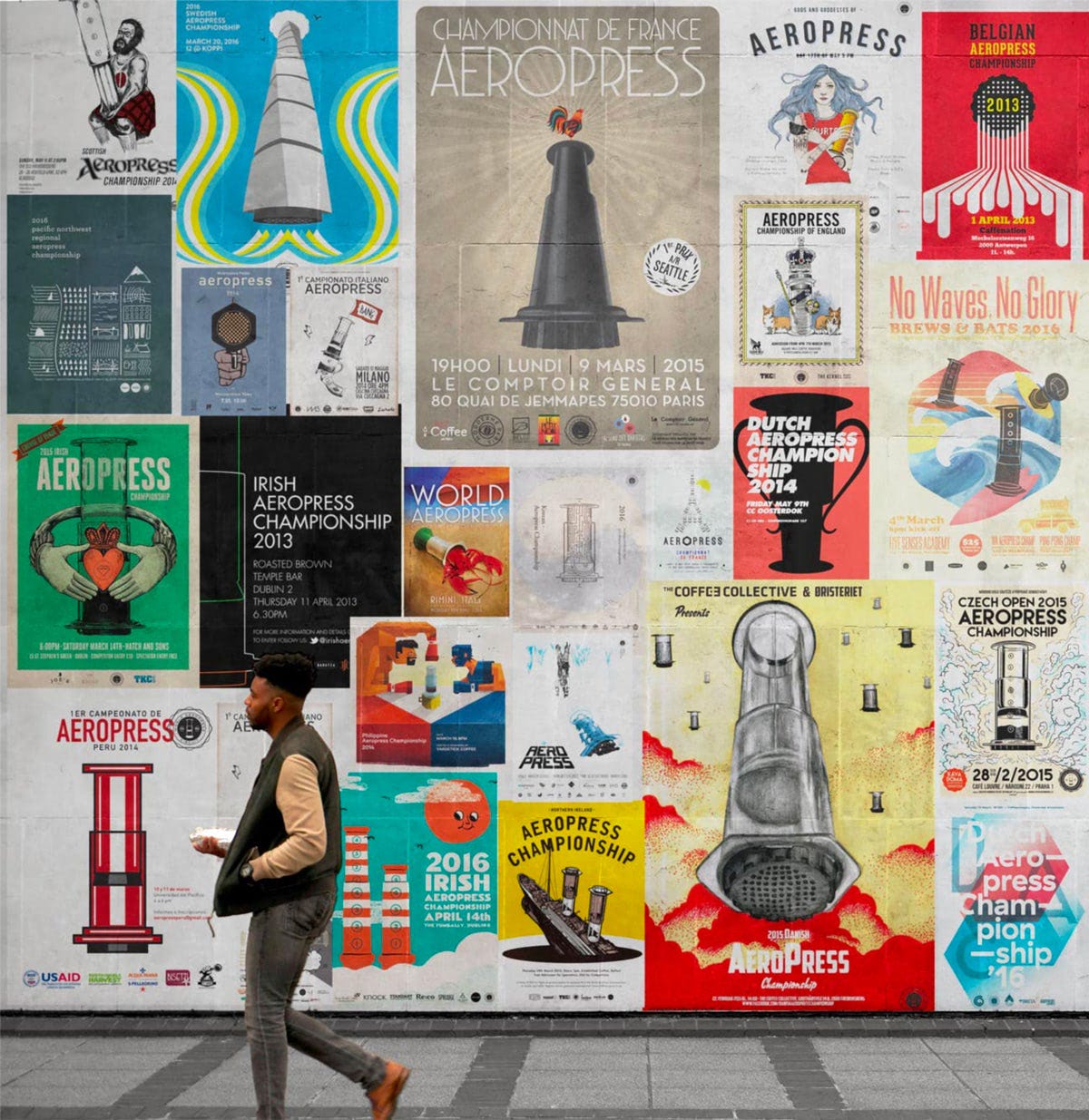Image of a man walking past a mural of various colorful AeroPress Championship posters
