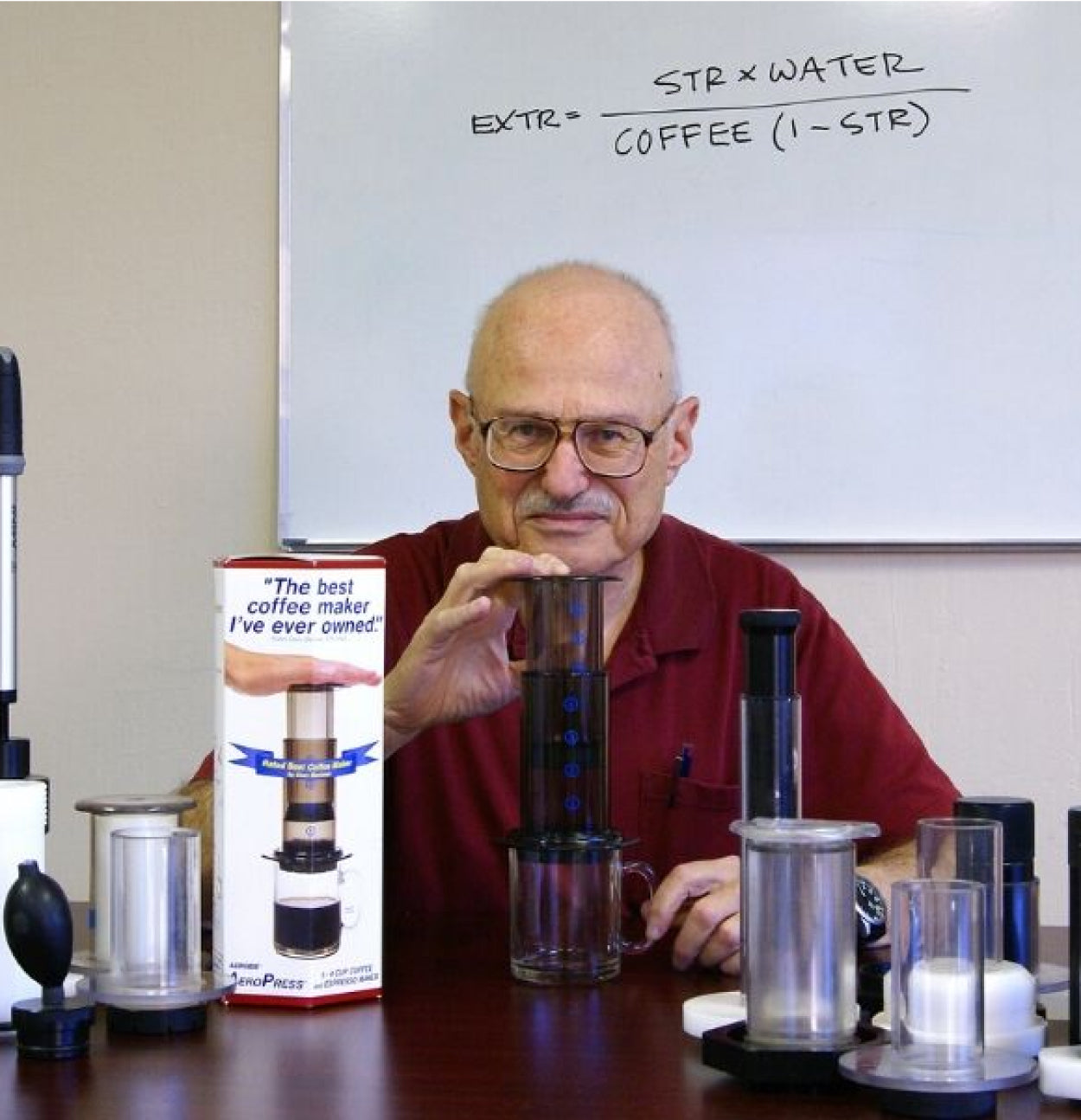 AeroPress inventor Alan Adler sitting among early prototypes of the AeroPress Original coffee maker